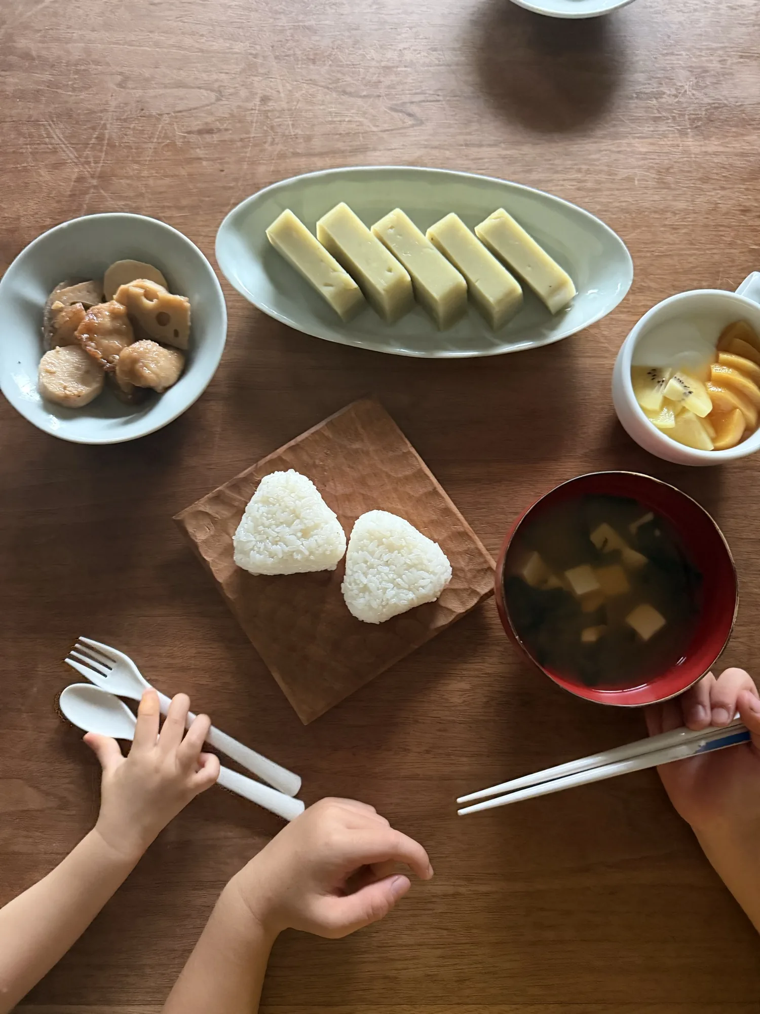 家族の手が伸びる、おにぎりとおかずの食卓